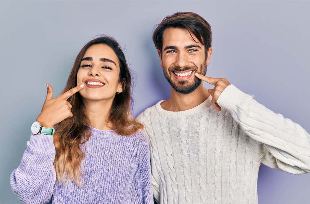 Young hispanic couple wearing casual clothes smiling cheerful showing and pointing with fingers teeth and mouth. dental health concept. Zahnimplantate