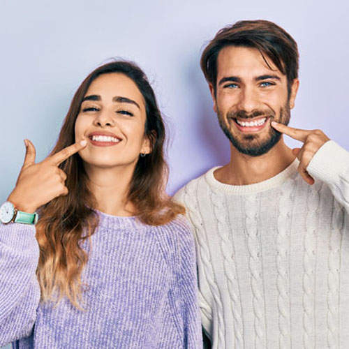Young hispanic couple wearing casual clothes smiling cheerful showing and pointing with fingers teeth and mouth. dental health concept.