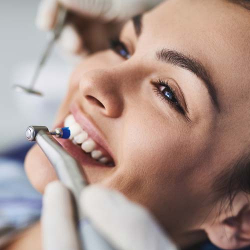 Charming young lady receiving teeth cleaning and polishing at clinic